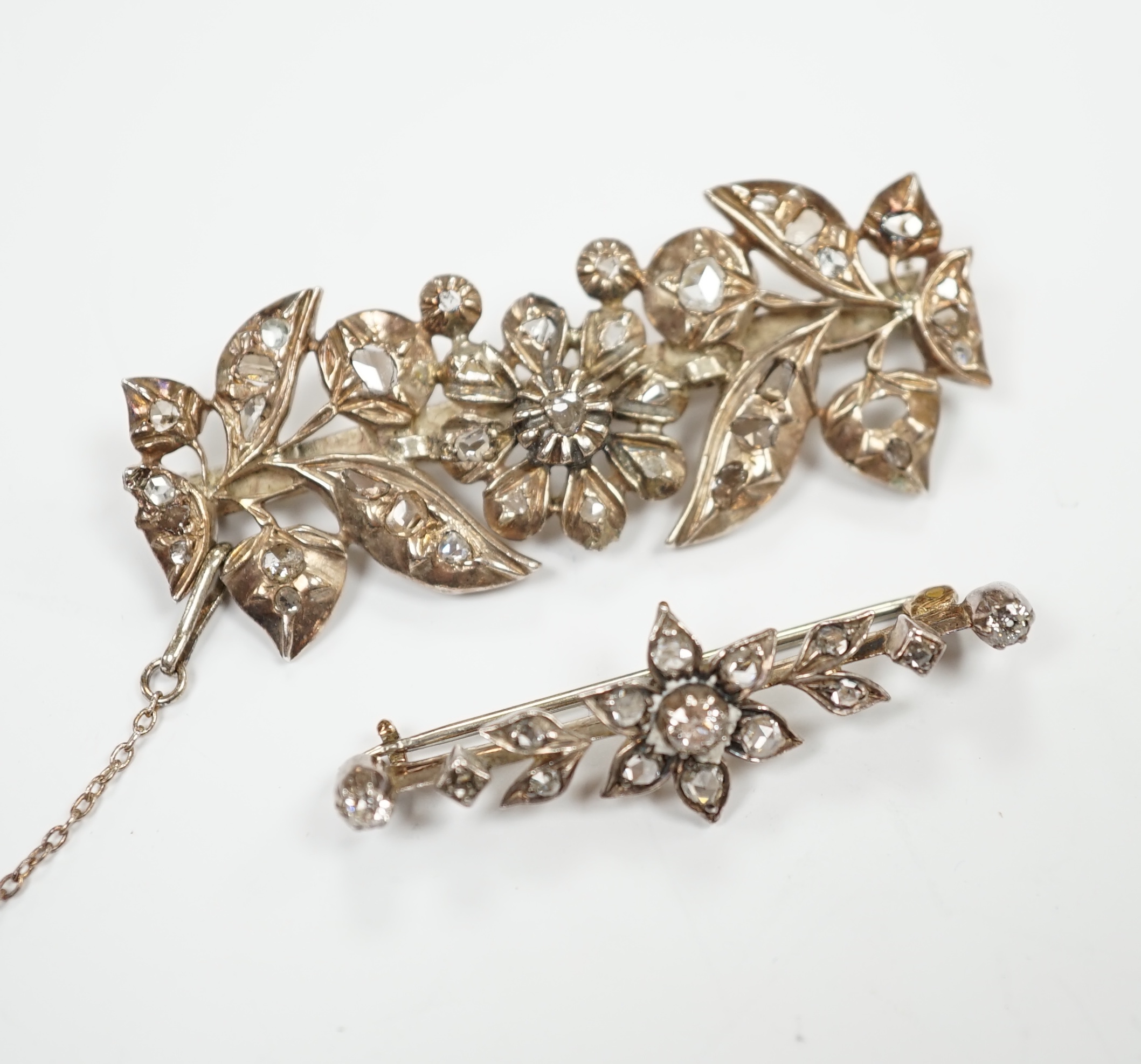 Two early 20th century yellow and white metal, rose cut diamond set foliate brooches, largest 51mm, gross weight 13.9 grams.